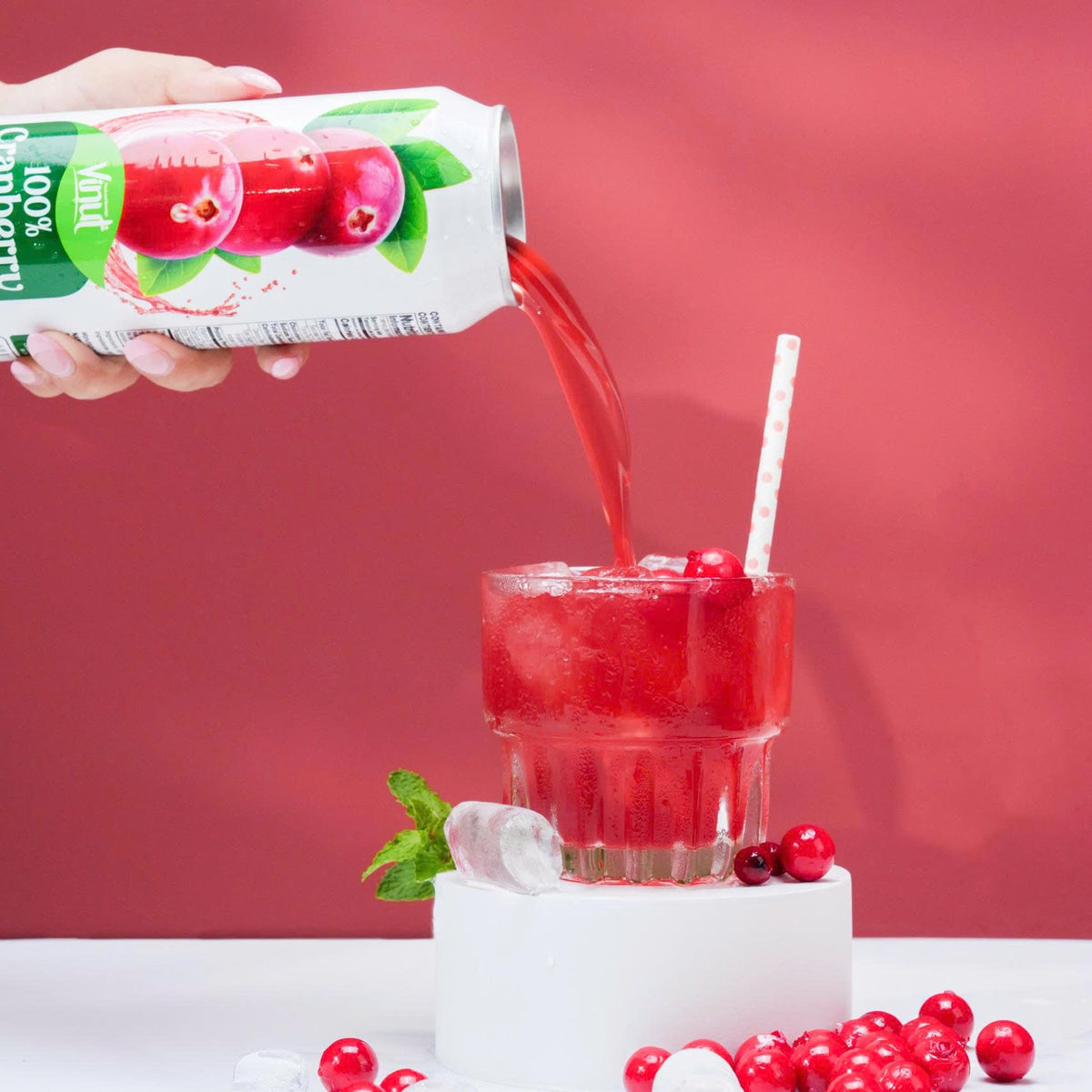 VINUT 100% cranberry juice can on table poured into glass with fresh tropical fruit
