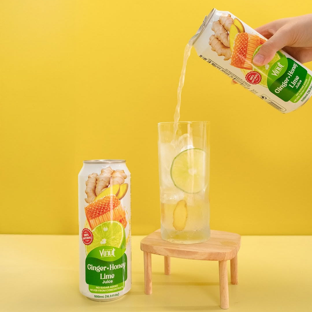 VINUT Ginger Honey Lime juice poured over ice with lime and ginger beside a 16.9 oz can