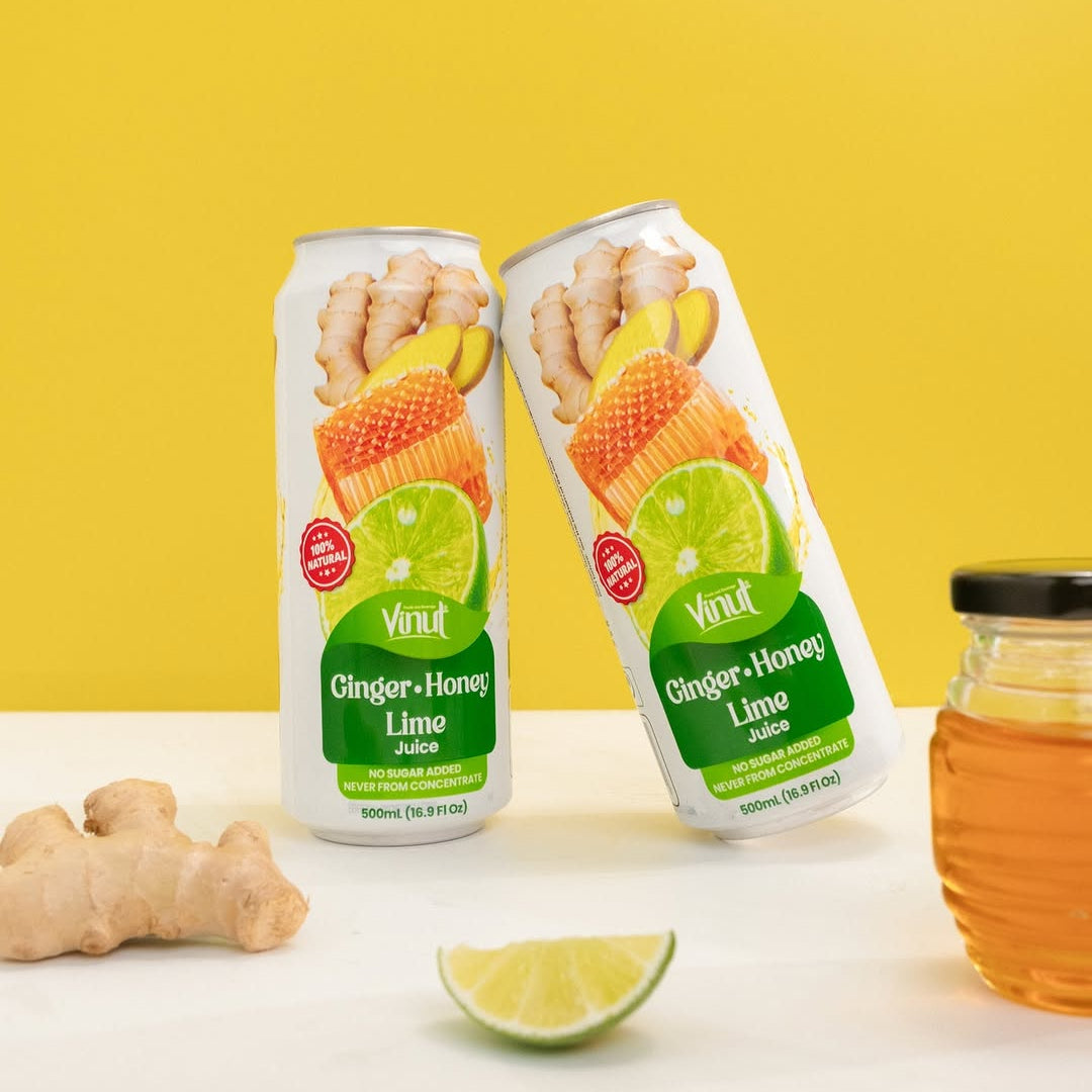 Two VINUT Ginger Honey Lime juice cans displayed with fresh ginger, honey and lime