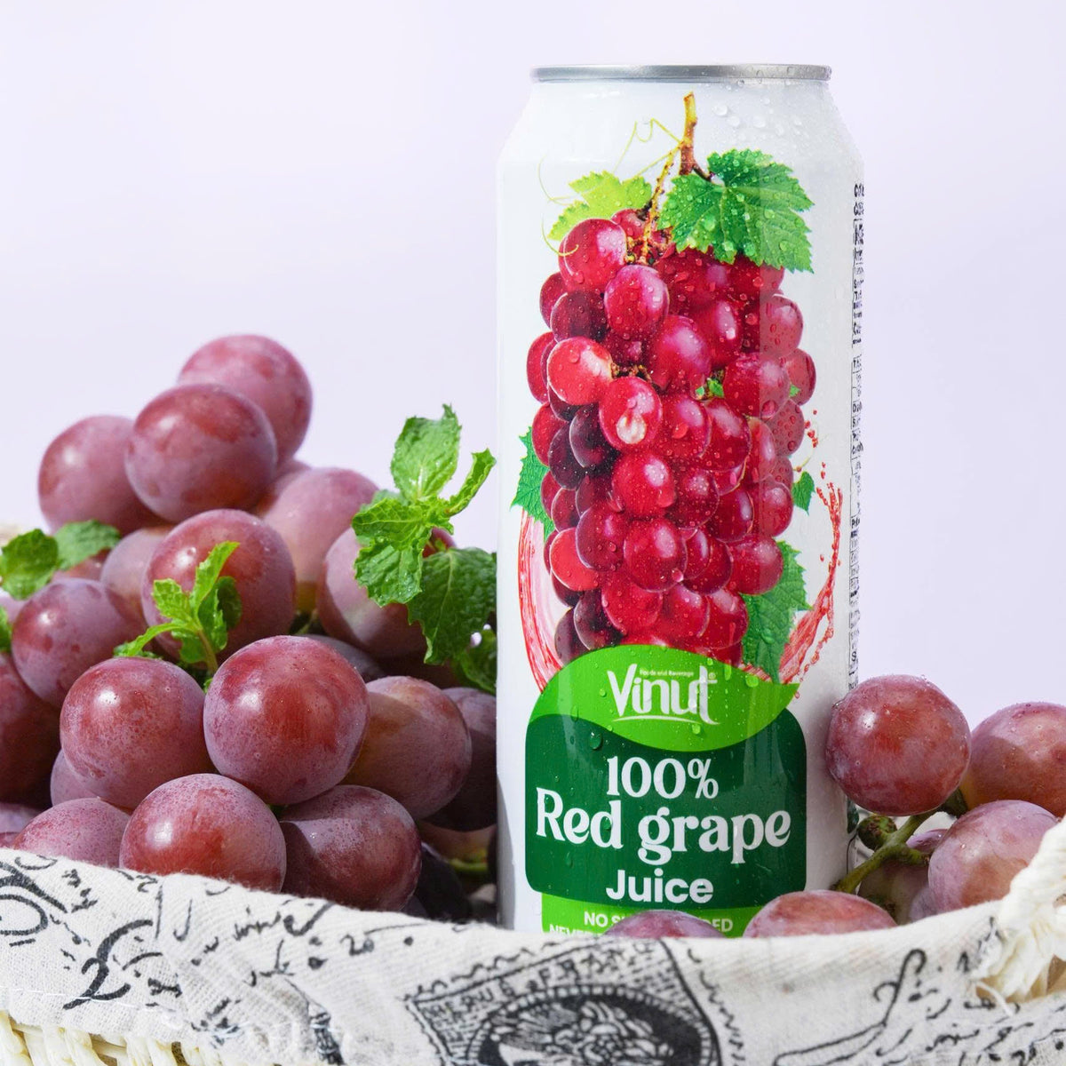 VINUT 100% grape juice can on table with fresh tropical fruit