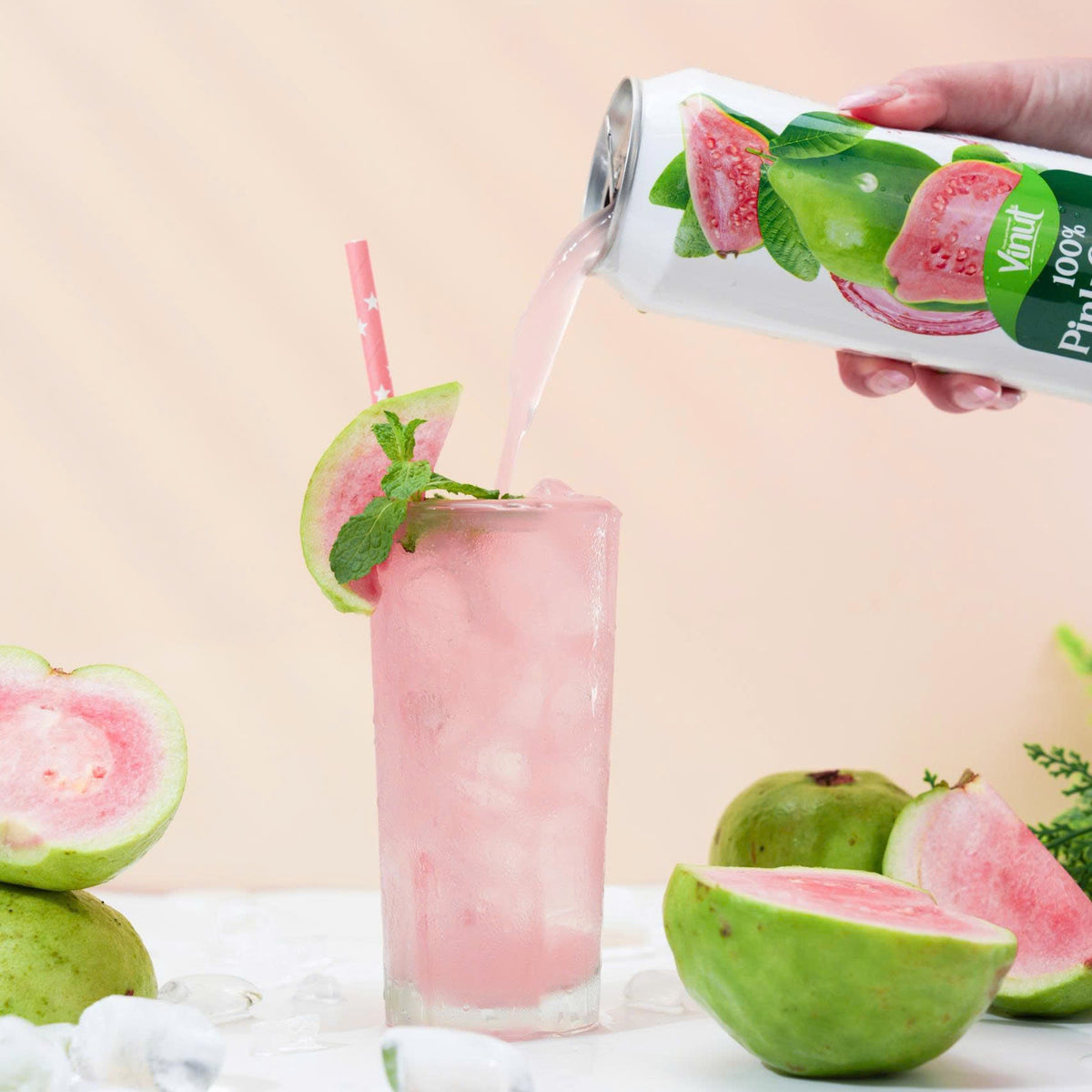 VINUT 100% pink guava juice can on table poured into glass with fresh tropical fruit